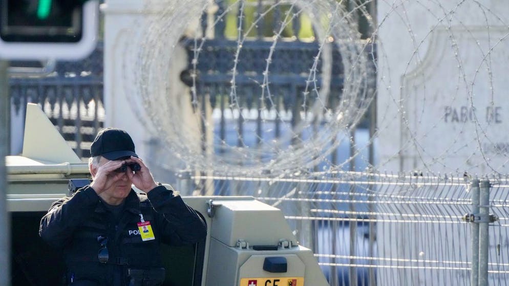 A police officer looks through a binoculars to guard the area in front of the 'Villa la Grange' ahead of the meeting of US President Joe Biden and Russian President Vladimir Putin at the villa, in Geneva, Switzerland, Wednesday, June 16, 2021. (AP Photo/Markus Schreiber)
