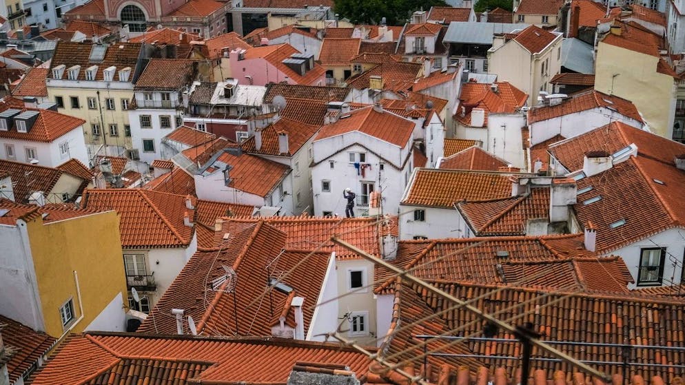 epa09282366 A man works on a roof at Bairro de Alfama in Lisbon, Portugal, 18 June 2021. The Portuguese cabinet announced on 17 June the ban on circulation to and from the Lisbon Metropolitan Area (AML) on weekends, starting at 15:00 on 18 June, due to the rise in cases of Covid-19 in this territory. EPA/MARIO CRUZ