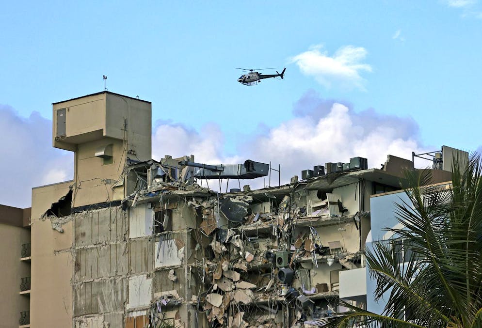 A Miami-Dade Police helicopter flies over Champlain Towers South Condo after a wing of the multistory building collapsed, Thursday, June 24, 2021, in Surfside, Fla. (David Santiago/Miami Herald via AP)