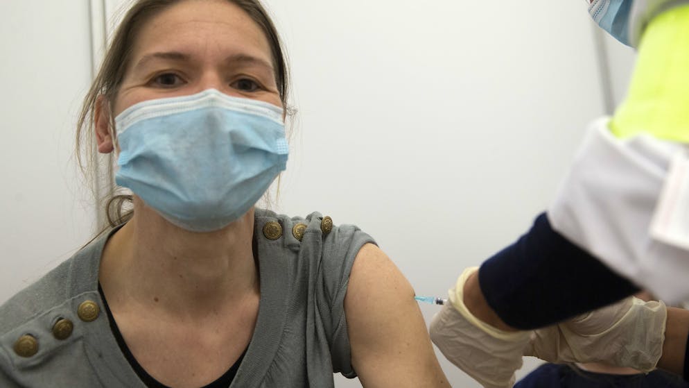 Un membre du staff medical vaccine contre le coronavirus COVID-19 une femme a l'aide du vaccin Moderna, lors du premier jour d'ouverture du Centre de vaccination de Palexpo, ce lundi 19 avril 2021 a Geneve. (KEYSTONE/Salvatore Di Nolfi)