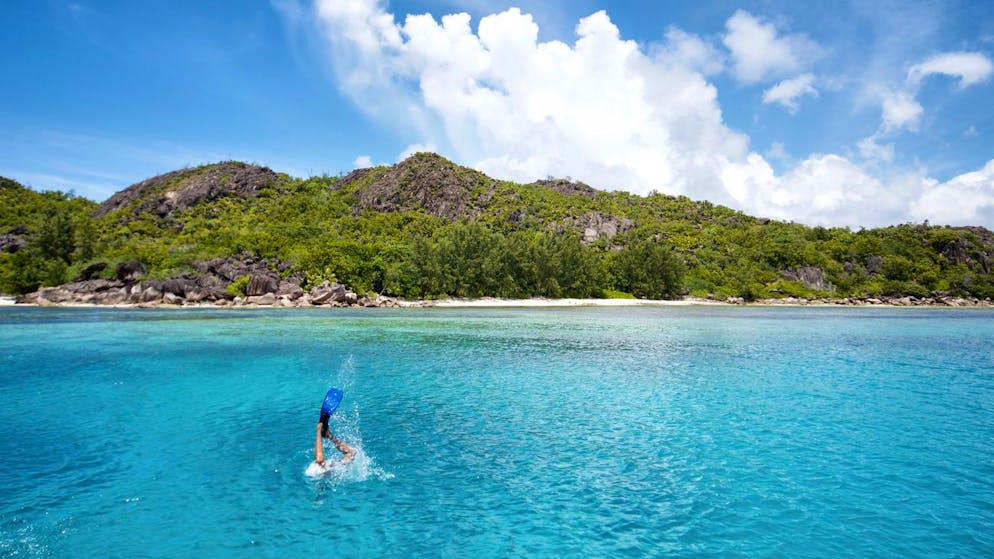 In this photo taken Tuesday, Feb. 20, 2018, a diver descends into the water in the Seychelles. The tiny island nation of the Seychelles is announcing a pioneering marine conservation plan as part of a debt swap deal with creditors, designating nearly a third of its ocean waters as protected areas and aiming to ensure its unique biodiversity. (Tate Drucker/The Nature Conservancy via AP)