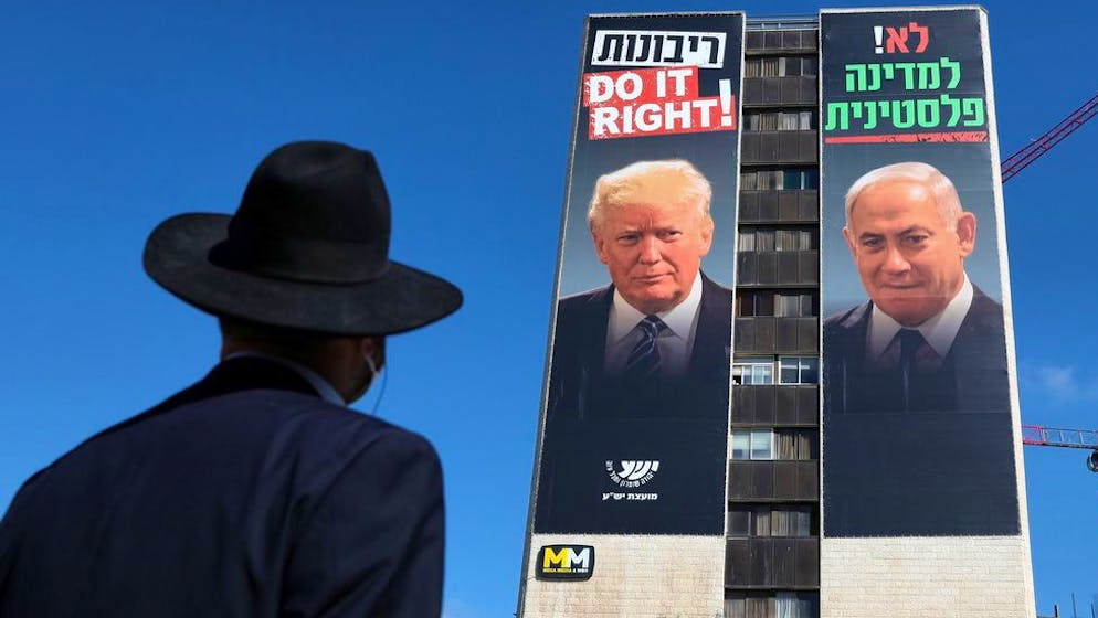 epa08510169 An Ultra Orthodox Jewish man looks at a billboard showing Israeli Prime Minister Benjamin Netanyahu (R) and US President Donald Trump (L) with the Hebrew caption