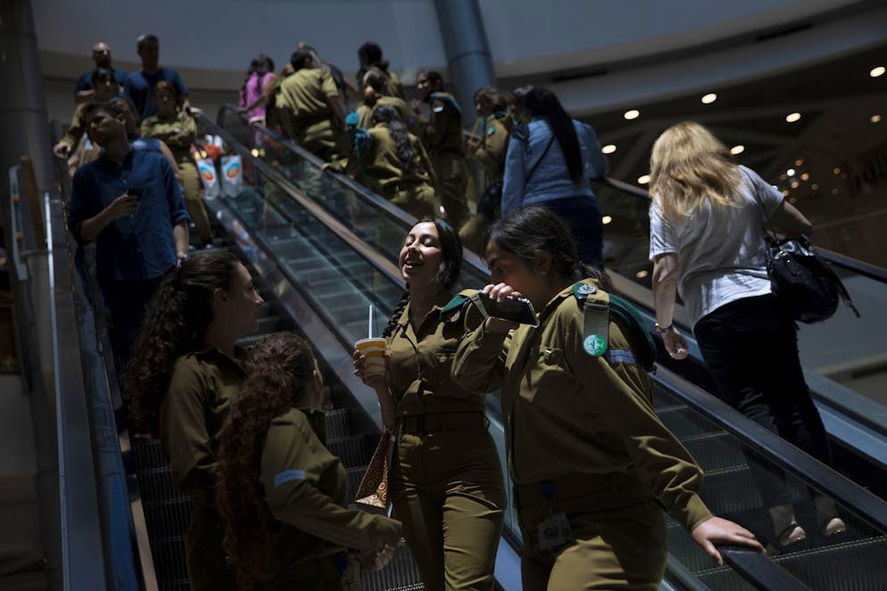 Les gens montent un escalator dans un centre commercial après la levée des restrictions exigeant des masques faciaux à l'intérieur, à Tel Aviv, le mardi 15 juin 2021.