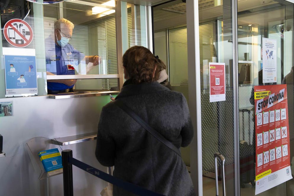 A Swiss border guard controls a passenger at the Swiss border crossing at the Geneve Aeroport as part of the new circulation arrangements put in place within the European Area to fight against the spread of coronavirus COVID-19, in Geneva, Switzerland, Monday, February 8, 2021. (KEYSTONE/Salvatore Di Nolfi)