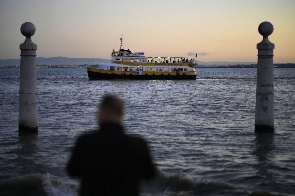 A sightseeing boat sails up the Tagus river in Lisbon, as the sun sets Monday, Dec. 6, 2021. (AP Photo/Armando Franca)