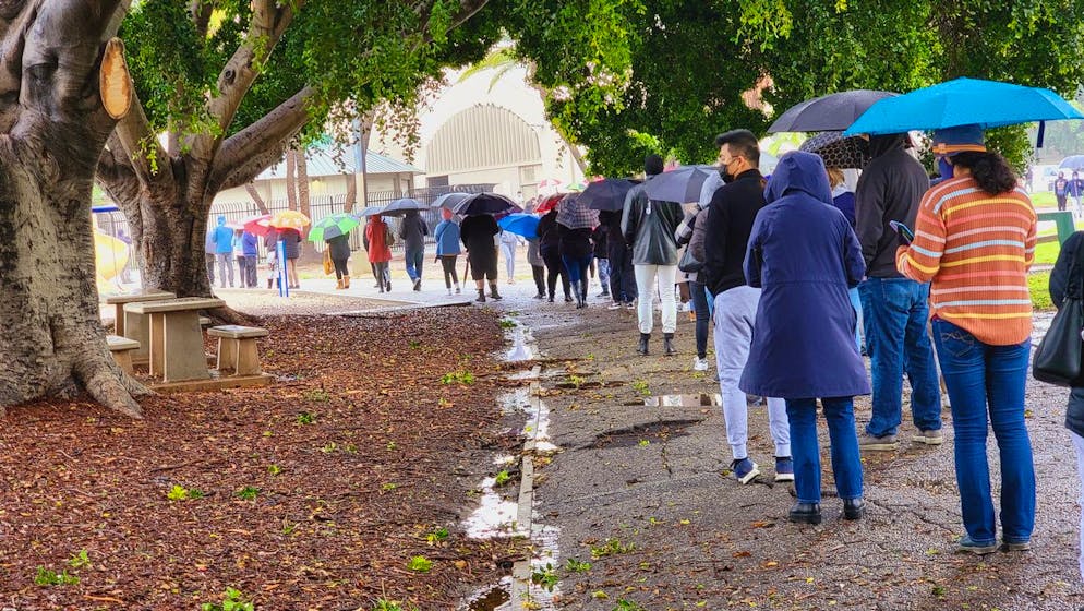 People stand in line under the rain for a free COVID-19 test outside the Lincoln Park Recreation Center in Los Angeles on Thursday, Dec. 30, 2021. More than a year after the vaccine was rolled out, new cases of COVID-19 in the U.S. have soared to their highest level on record at over 265,000 per day on average, a surge driven largely by the highly contagious omicron variant. (AP Photo/Damian Dovarganes)