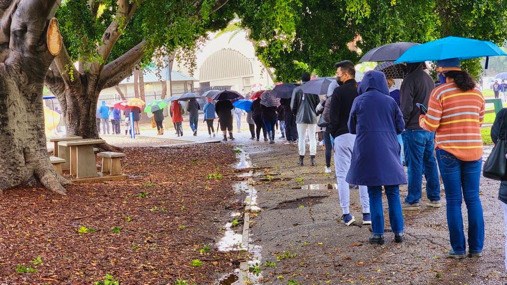 People stand in line under the rain for a free COVID-19 test outside the Lincoln Park Recreation Center in Los Angeles on Thursday, Dec. 30, 2021. More than a year after the vaccine was rolled out, new cases of COVID-19 in the U.S. have soared to their highest level on record at over 265,000 per day on average, a surge driven largely by the highly contagious omicron variant. (AP Photo/Damian Dovarganes)