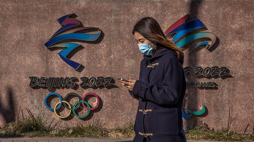 epa09614041 A woman wearing a face mask walks past the 2022 Beijing Winter Olympic and Paralympic emblems next to the headquarters of the 2022 Beijing Winter Olympics organising committee, at the Shougang Industrial Park, which will be used as a venue for hosting sport and other events during Beijing 2022 Winter Olympics, in Beijing, China, 01 December 2021. According to China's epidemiologist experts, the new Omicron COVID-19 variant, which poses a high risk globally, at this moment wouldn't have a strong impact on China, which is scheduled in two months to host The 2022 Beijing Winter Olympics followed by the Paralympics. EPA/ROMAN PILIPEY