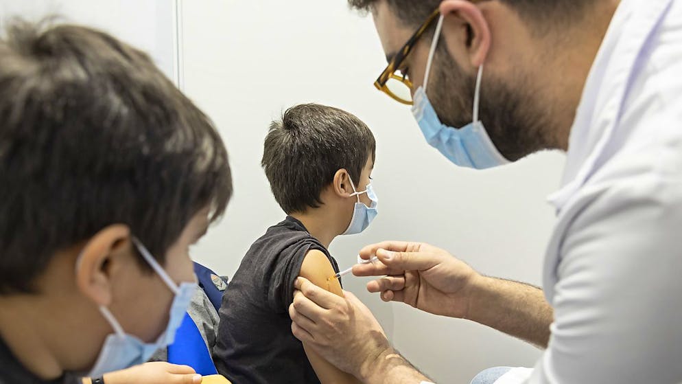 À Genève, le jeune Abel, 8 ans, reçoit son vaccin contre le Covid-19 sous les yeux de son frère jumeau Santiago.