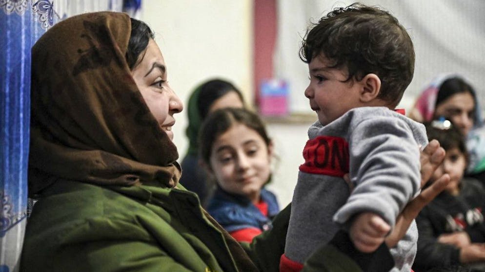 Sohail Ahmadi (R), who was separated from his parents at the airport in the chaos of the US evacuation of Afghanistan in August 2021, is held by the wife of Hamid Safi, a taxi driver who found Sohail on the ground at Kabul airport and tracked down the family, at Sohail's grandfather's house in Kabul on January 9, 2022. (Photo by Mohd RASFAN / AFP)