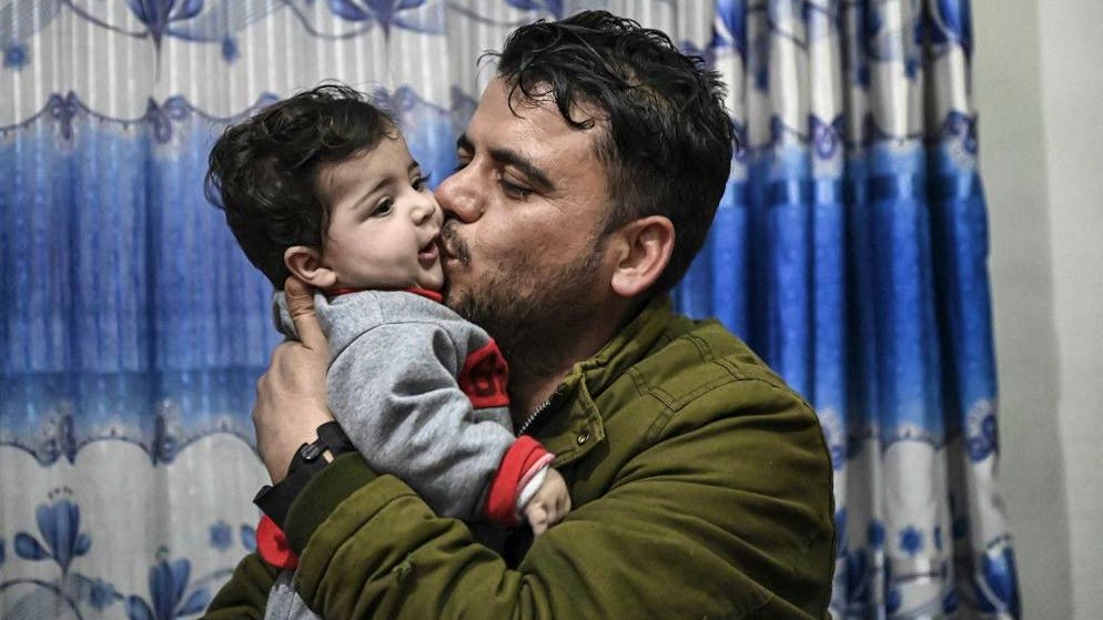 Hamid Safi, a taxi driver who found Sohail Ahmadi on the ground at Kabul airport and tracked down the family, kisses Sohail, who was separated from his parents at the airport in the chaos of the US evacuation of Afghanistan in August 2021, at Sohail's grandfather's house in Kabul on January 9, 2022. (Photo by Mohd RASFAN / AFP)