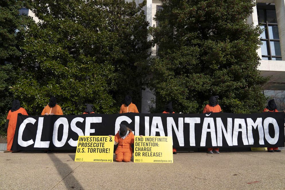 Demonstrators wearing orange prisoner jumpsuits and a black hood, those symbolize Guantanamo Bay detainees, hold a banner asking to close Guantanamo on Capitol Hill in Washington, Tuesday, Dec. 7, 2021. Protesters demanded the closure of the detention center at the U.S. Naval Base in Guantanamo Bay, in Cuba. (AP Photo/Jose Luis Magana)