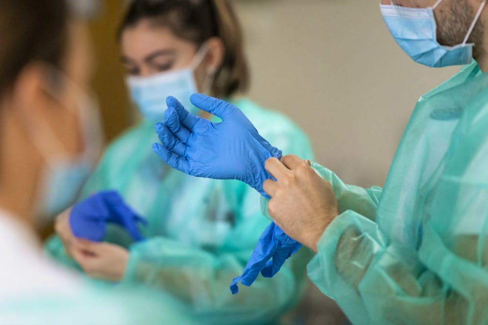 Pflegende ziehen sich vor einem Patientenbesuch Schutzhandschuhe an, auf der Abteilung fuer COVID-Patienten im HFR Freiburg Kantonsspital, am Donnerstag, 26. November 2020 in Fribourg. (KEYSTONE/Alessandro della Valle)