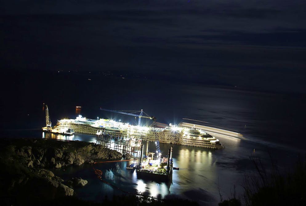Sur cette photo prise avec une vitesse d'obturation lente, les lumières illuminent le bateau de croisière Costa Concordia, sur l'île toscane de Giglio, en Italie, le lundi 13 janvier 2014.