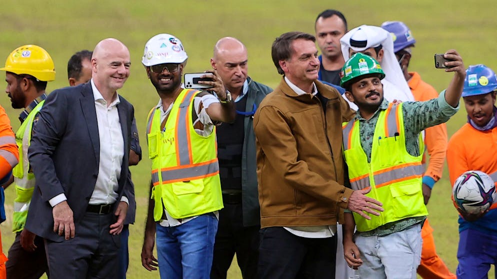 Brazilian President Jair Bolsonaro (C-R) and FIFA president Gianni Infantino (C-L) meet with workers at Lusail Stadium, the 80,000-capacity venue that will host the FIFA World Cup final in December 2022, around 20 kilometres north of the Qatari capital Doha on November 17, 2021. (Photo by KARIM JAAFAR / AFP) (Photo by KARIM JAAFAR/AFP via Getty Images)
