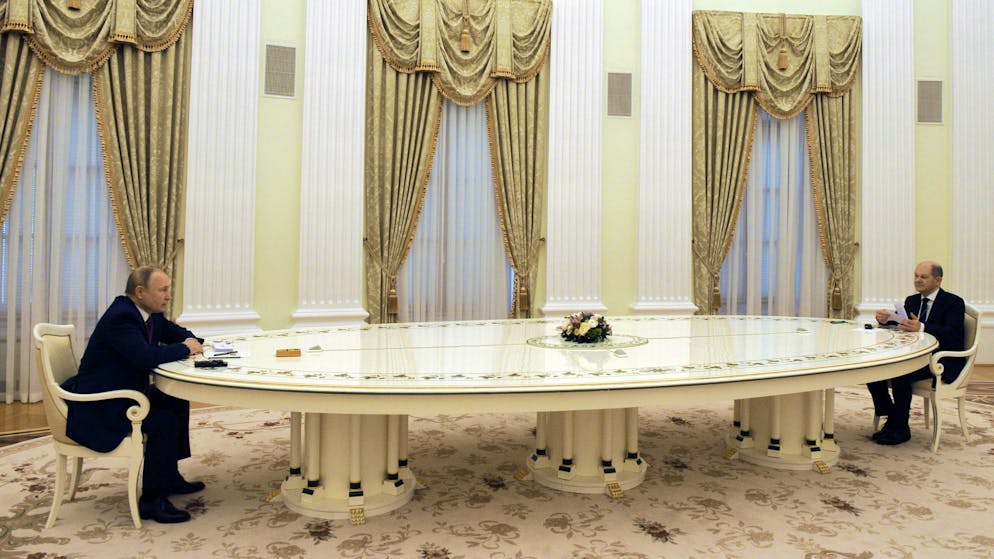 Russlands Präsident Wladimir Putin (links) und Bundeskanzler Olaf Scholz (SPD) sitzen sich an einem langen Tisch im Kreml gegenüber.