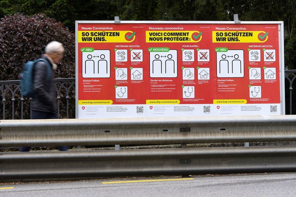 Une personne marche devant des affiches de l?office federal de la sante publique (OFSP), rappelant les regles pour se proteger du coronavirus, ce vendredi 15 mai 2020, a Fribourg. (KEYSTONE/Anthony Anex)