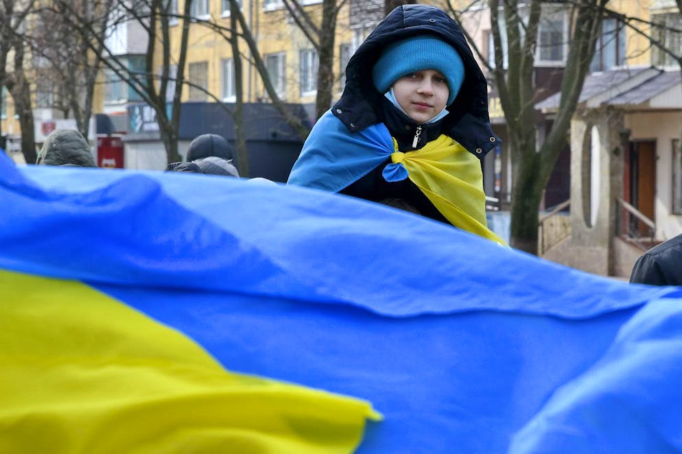 A boy draped a Ukrainian national flag over his shoulders attends a march in support of Unity of Ukraine in Kramatorsk, Ukraine, Wednesday, Feb. 16, 2022. Tensions spiked anew over Ukraine on Thursday with conflicting claims over whether Russia had drawn down troops it has been massing for weeks around Ukraine, escalating hostilities in Ukraine's separatist-controlled east and intensified diplomacy. (AP Photo/Andriy Andriyenko)
