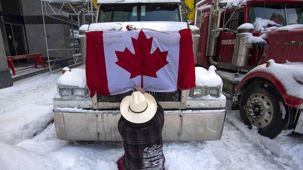 Ein protestierender Trucker bereitet sich am 19. Februar 2022 in Ottawa auf die Abfahrt vor und nimmt dafür die kanadische Flagge von seinem Fahrzeug ab.
