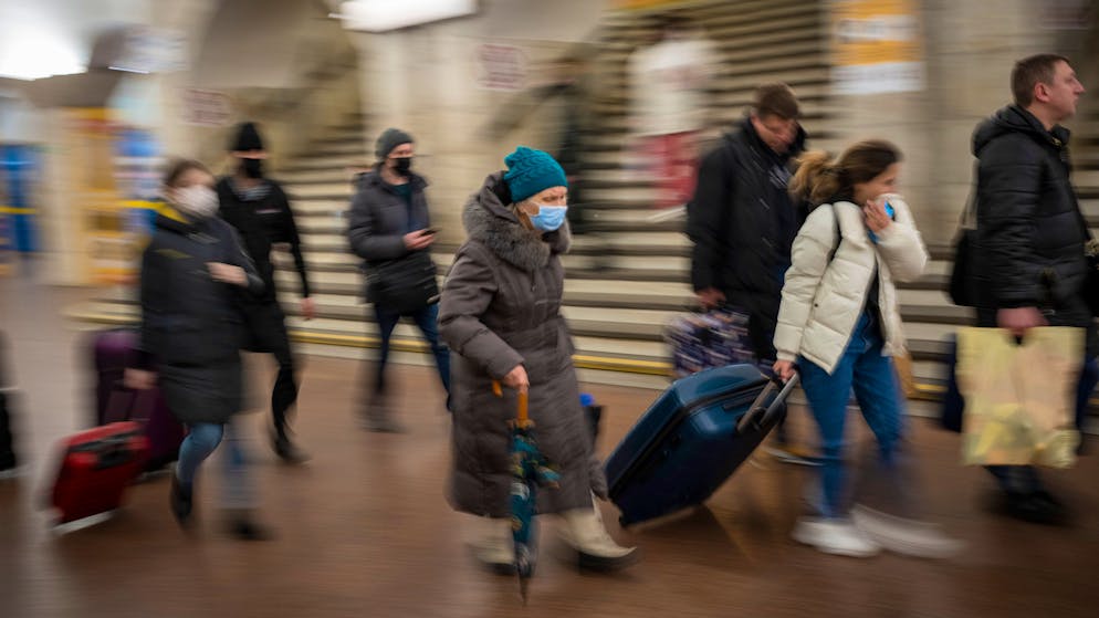 People walk in a subway to get a train as they leave the city of Kyiv, Ukraine, Thursday, Feb. 24, 2022. Russian President Vladimir Putin on Thursday announced a military operation in Ukraine and warned other countries that any attempt to interfere with the Russian action would lead to 
