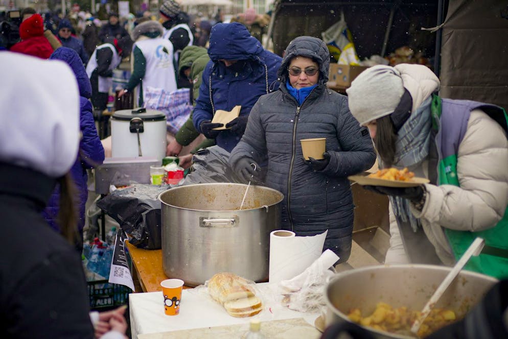 Des volontaires servent des plats chauds aux réfugiés fuyant le conflit de l'Ukraine voisine à la frontière roumano-ukrainienne, à Siret, en Roumanie, le mercredi 2 mars 2022.