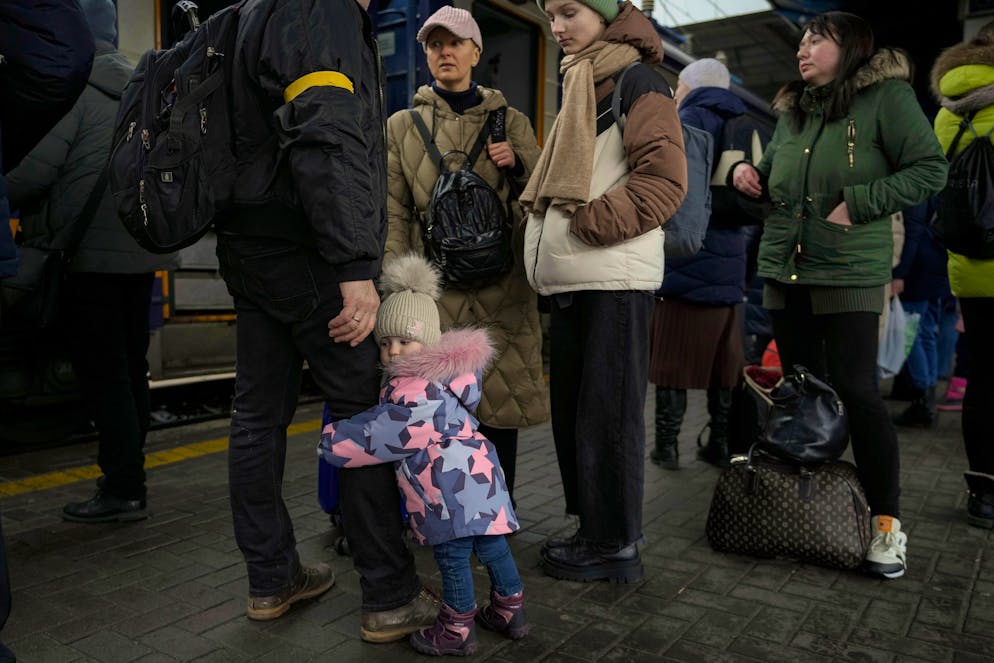 A child clutches a man's leg before boarding a Lviv bound train, in Kyiv, Ukraine, Thursday, March 3, 2022. Ukrainian President Volodymyr Zelenskyy's office says a second round of talks with Russia aimed at stopping the fighting that has sent more than 1 million people fleeing over Ukraine's borders, has begun in neighboring Belarus, but the two sides appeared to have little common ground. (AP Photo/Vadim Ghirda)