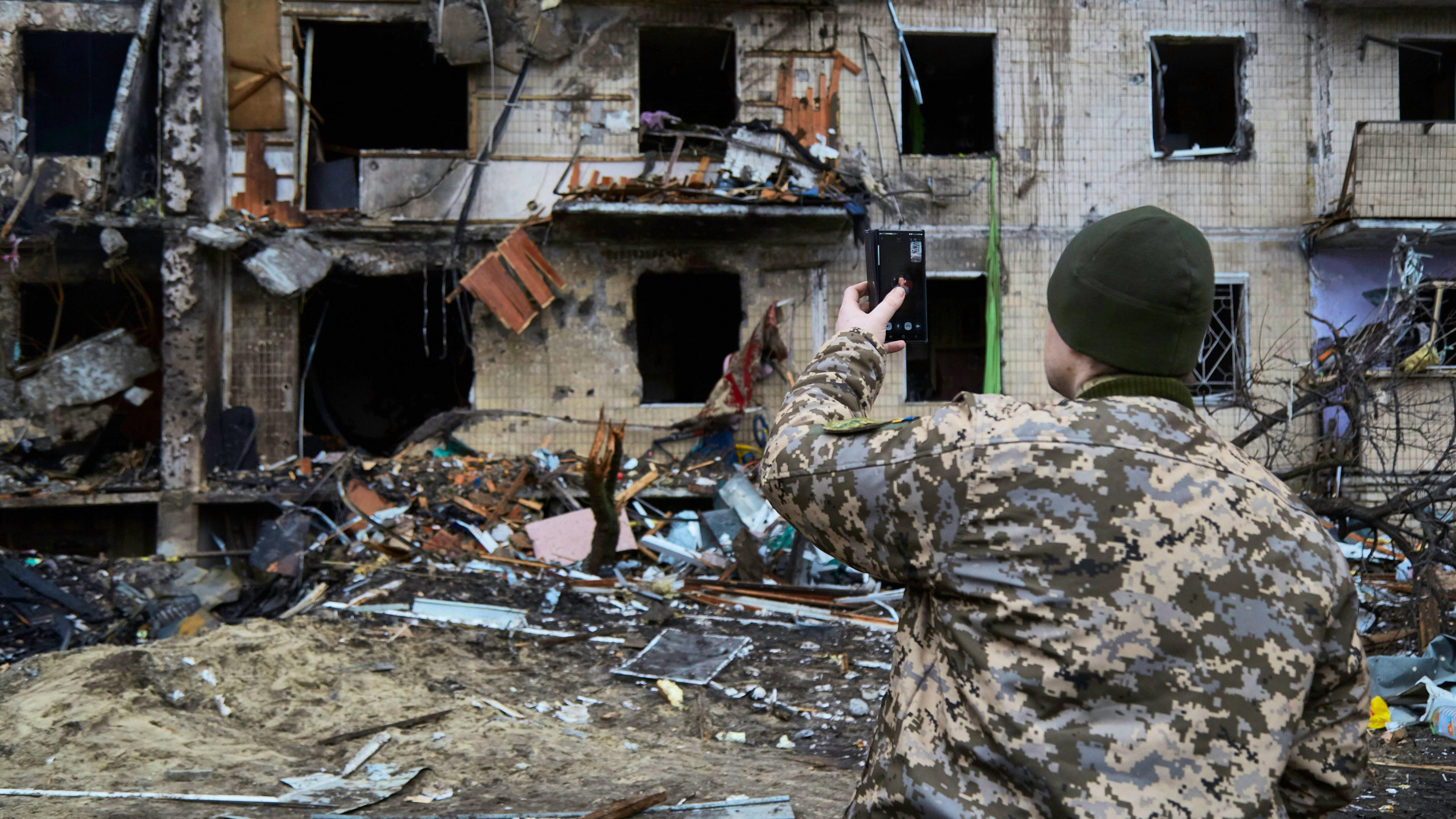 Wie geht man am besten mit der Nachrichtenflut um? Ein Soldat dokumentiert mit seinem Handy Zerstörungen in Kiew.&nbsp;