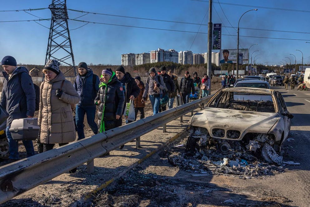 epa09815777 Residents walk past a burnt car as they flee from the frontline town of Irpin, Kyiv (Kiev) region, Ukraine, 10 March 2022. Thousands of residents are feeling Irpin and Bucha, as well as other settlements near Kyiv which were the most affected by the Russian army invasion. EPA/ROMAN PILIPEY