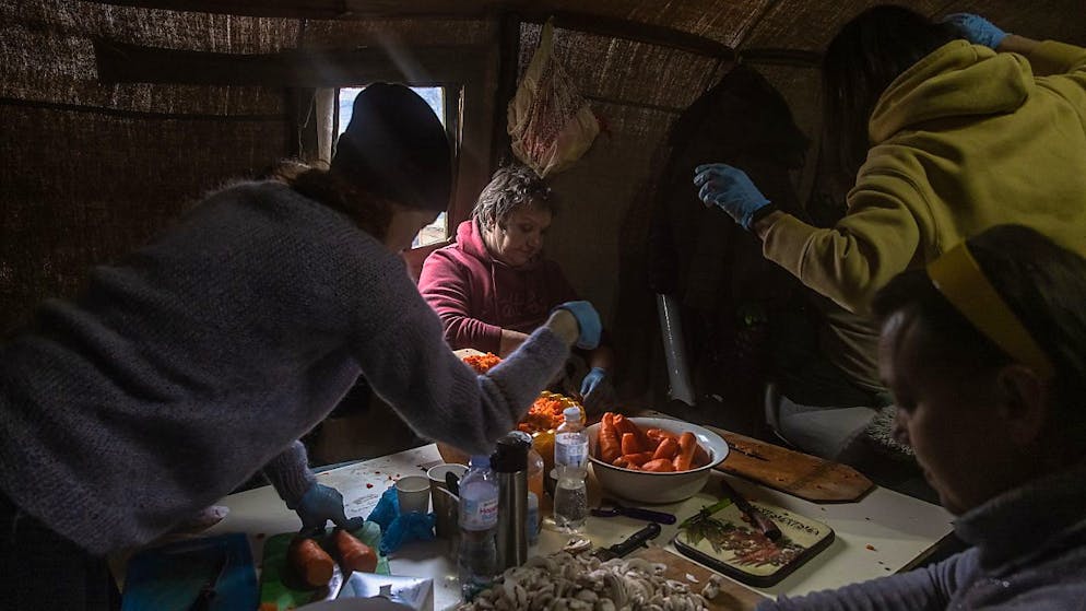Donne ucraine intente a cucinare in una tenda vicino a un checkpoint di Kiev