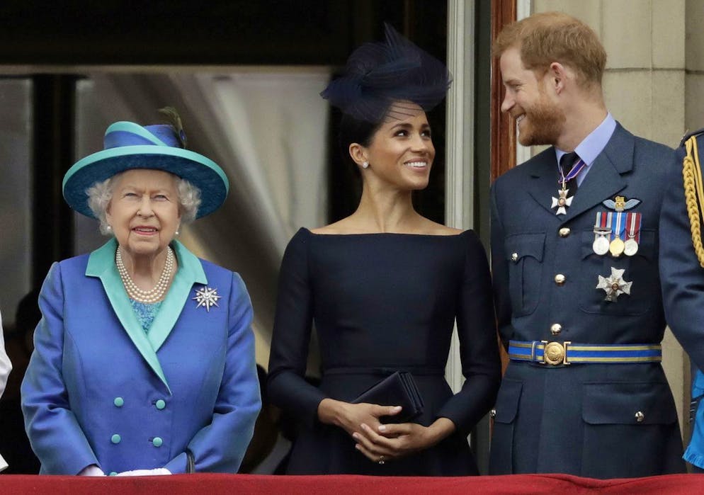 La reine Elizabeth II, Meghan la duchesse de Sussex et le prince Harry regardent un défilé aérien d'avions de la Royal Air Force passer au-dessus de Buckingham Palace à Londres, le 10 juillet 2018. 