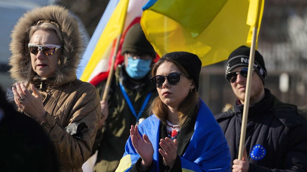 A woman is wrapped in the Ukrainian flag as she participates in a demonstration in front of a building housing Russian diplomats in Warsaw, Poland, Sunday, March 13, 2022. Russia has escalated attacks in western Ukraine, striking a military base where its troops had trained with NATO forces and bringing the conflict closer to Poland and other members of the bloc. (AP Photo/Czarek Sokolowski)