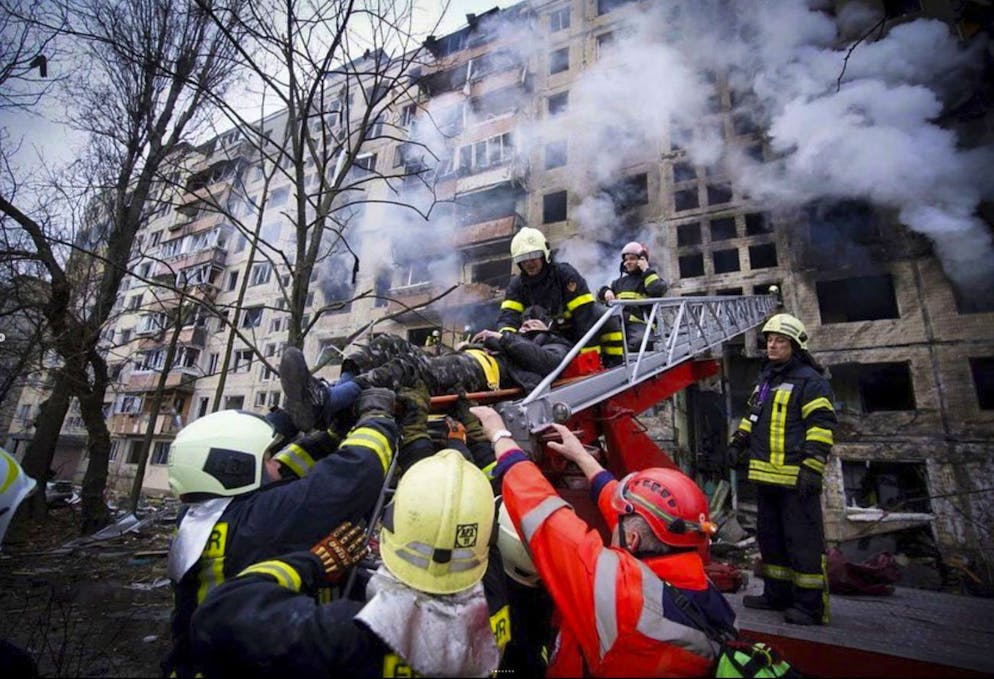 In this photo released by Ukrainian State Emergency Service press service, firefighters evacuate a man from an apartment building hit by shelling in Kyiv, Ukraine, Monday, March 14, 2022. (Ukrainian State Emergency Service via AP)