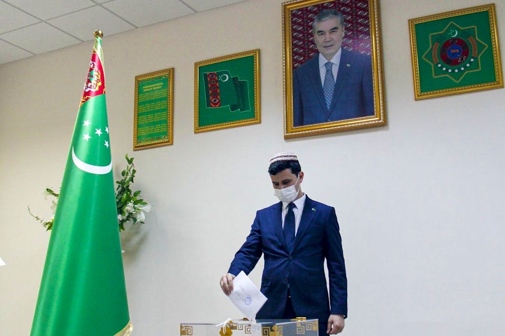 A man casts his ballot at a polling station during presidential elections in Ashgabat, Turkmenistan, Saturday, March 12, 2022, with the portrait of President Gurbanguly Berdymukhamedov in the background. Turkmenistan citizens have voted in an election that could establish a political dynasty for the gas-rich Central Asian nation's leader. President Gurbanguly Berdymukhamedov, 64, announced the snap presidential election last month, setting the stage for his 40-year old son Serdar to take over. (AP Photo/Alexander Vershinin)