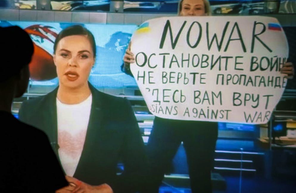 epa09826233 A woman watches a recorded feed of the Russian Channel One's evening news broadcast TV show in which an employee enters Ostankino on-air TV studio with a poster reading ''No War. Stop the war. Don't believe the propaganda. You are being lied to here