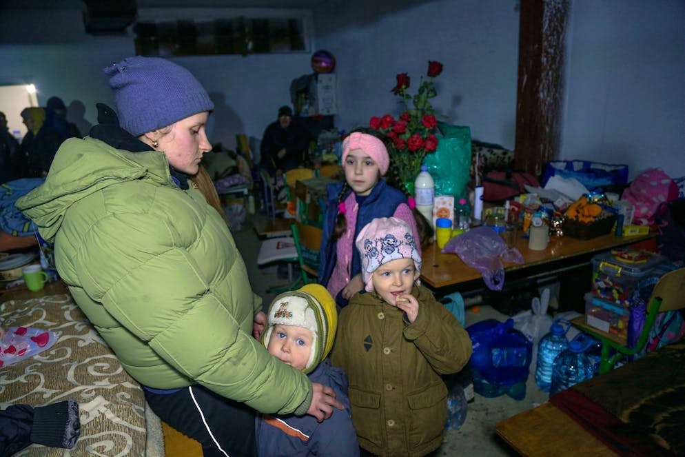 A woman and children sheild from shelling in a school bomb shelter in Sartana village which is under the Government of the Donetsk People's Republic control, 17 km ( 11 miles) northeast of Mariupol, eastern Ukraine, Wednesday, March 16, 2022. (AP Photo/Alexei Alexandrov)