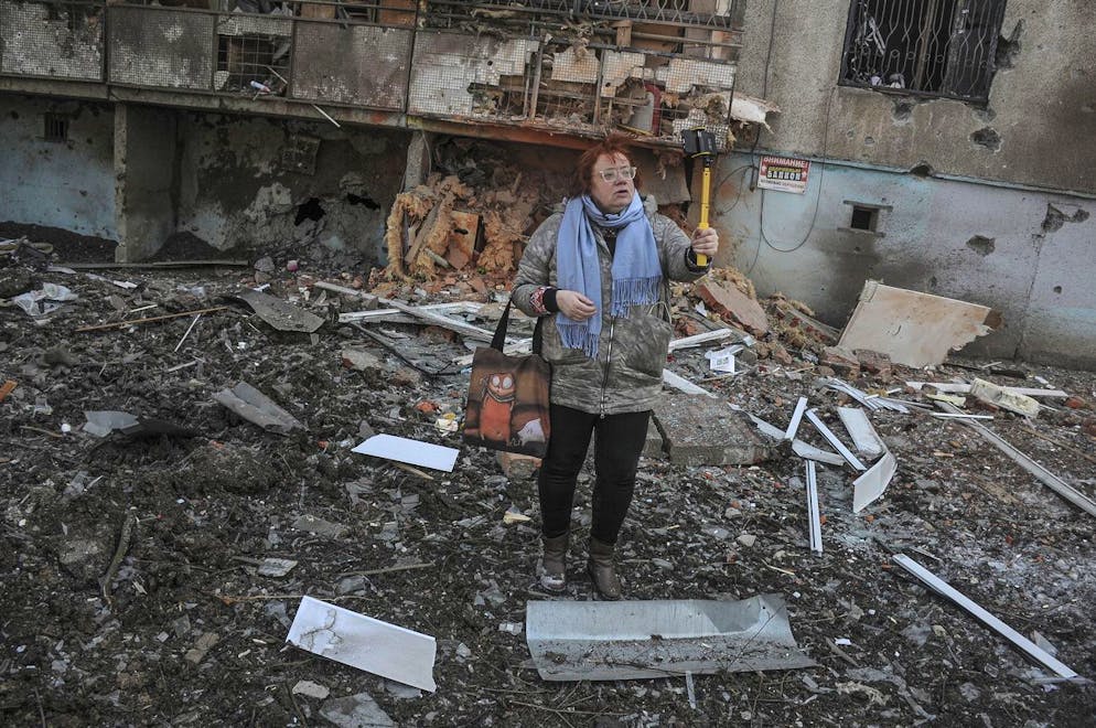 epa09831194 A woman poses for a photo next to a damaged building in the aftermath of a shelling in Kharkiv, Ukraine, 17 March 2022, as the Russian invasion of Ukraine enters its fourth week. EPA/VASILIY ZHLOBSKY