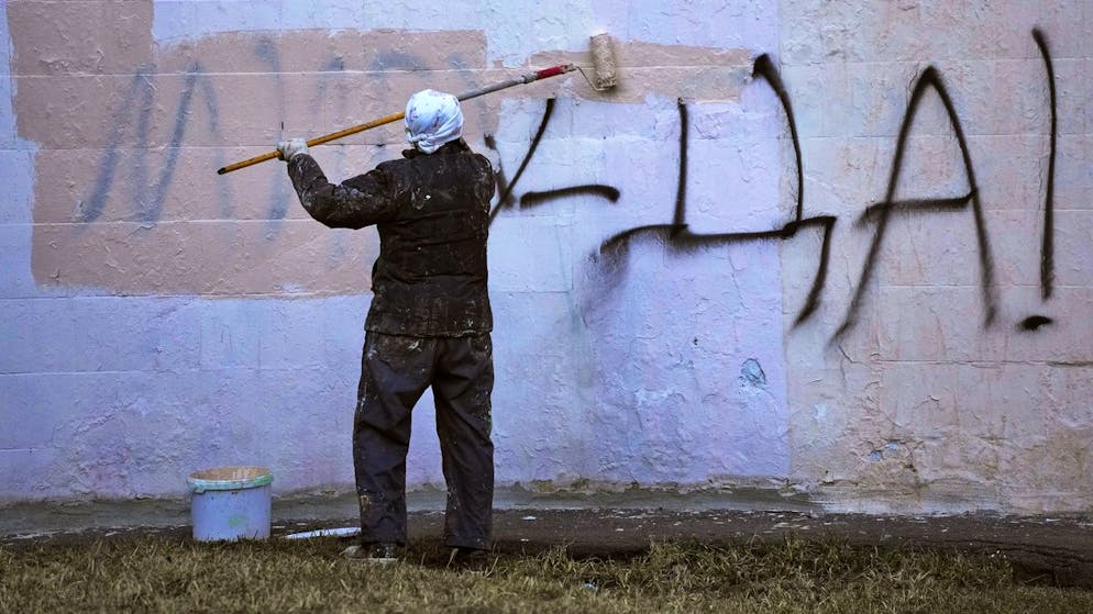 A worker paints over a writing reading 'Yes to Peace!'  on a wall of an apartment building in St.  Petersburg, Russia, Friday, March 18, 2022. (AP Photo)