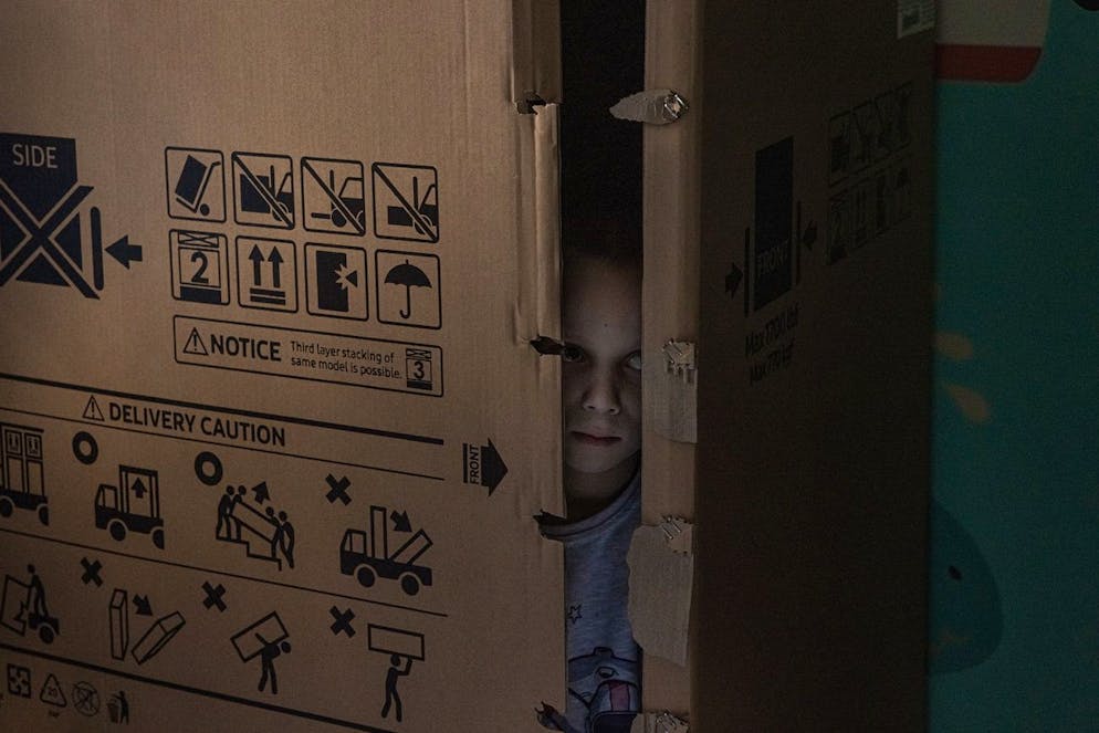 epa09837678 A boy, patient at the hospital, hides inside a big carton box while hearing air raid sirens during the visit of clowns at the Ohmatdyt hospital in Kyiv, Ukraine, 19 March 2022 (issued 20 March 2022). According to the figures provided by the United Nations as of 18 March, 64 children have been killed and 78 injured, mostly caused by shelling and airstrikes since the beginning of Russia's armed attack on Ukraine, although the actual toll is believed to be much higher. UNICEF says more than 1.5 million children have fled Ukraine as refugees since 24 February and many others were displaced inside the country as a result of the Russian attack. EPA/ROMAN PILIPEY ATTENTION: This Image is part of a PHOTO SET