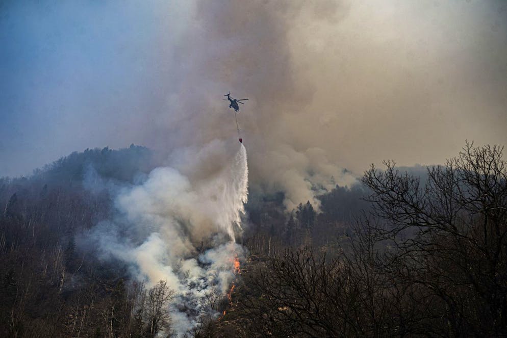 Ein Helikopter bei Loescharbeiten des Waldbrandes oberhalb von Verdasio im Centovalli Tal, am Freitag, 25. Maerz 2022. Ausgebrochen war der Waldbrand am Mittwoch, teilte die Tessiner Kantonspolizei mit. (KEYSTONE/Ti-PRESS/Samuel Golay)