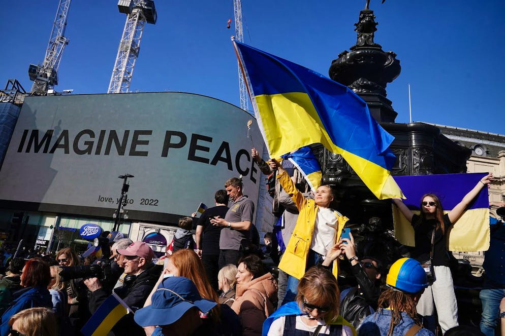 People gather in front of the Yoko Ono 'Imagine Peace' sign at Piccadilly, in London, Saturday March 26, 2022, during a solidarity march for Ukraine. (Aaron Chown/PA via AP)