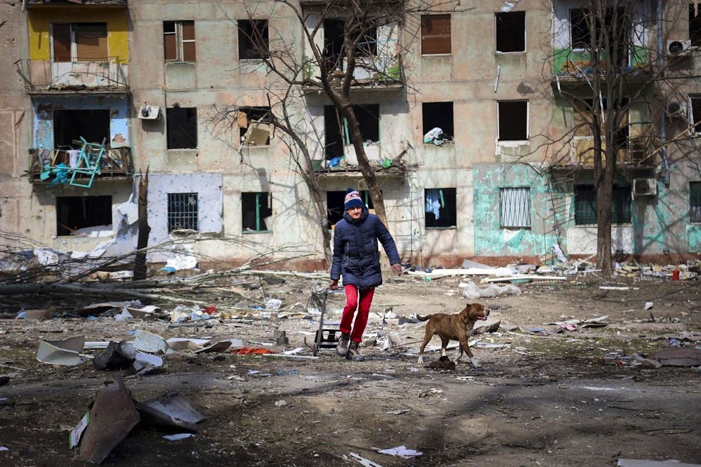 A man walks with his dog near an apartment building damaged by shelling from fighting on the outskirts of Mariupol, Ukraine, in territory under control of the separatist government of the Donetsk People's Republic, on Tuesday, March 29, 2022. (AP Photo/Alexei Alexandrov)