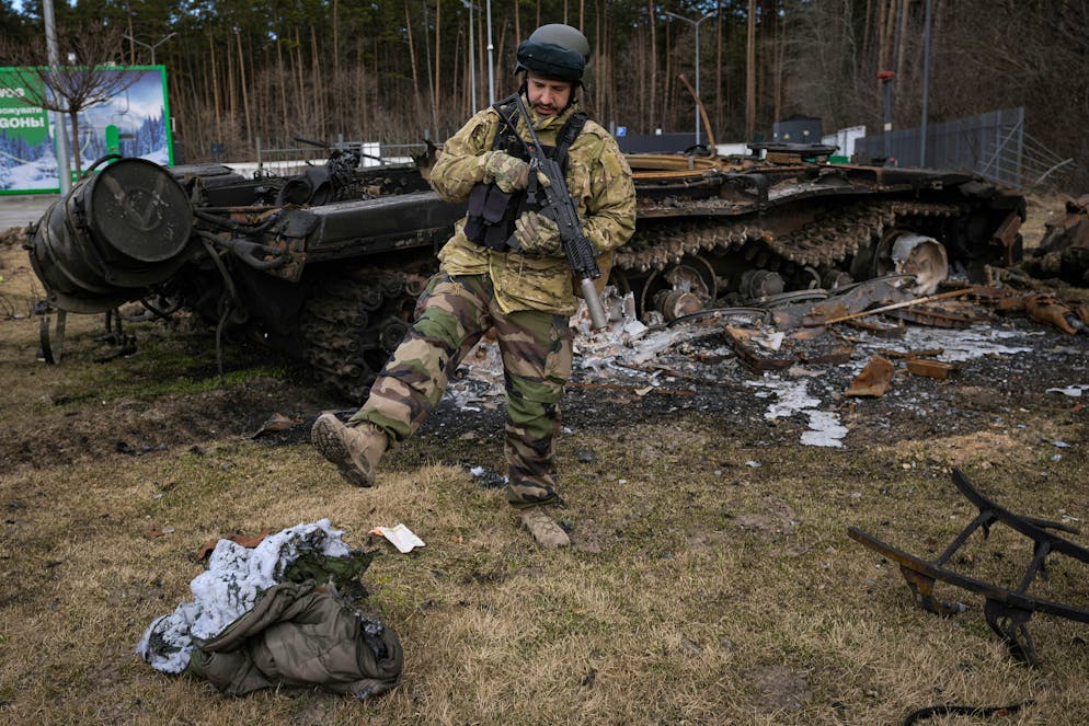 A Ukrainian serviceman kicks a burnt sleeping bag near the wreck of a Russian tank in Stoyanka, Ukraine, Sunday, March 27, 2022. Ukrainian President Volodymyr Zelenskyy accused the West of lacking courage as his country fights to stave off Russia's invading troops, making an exasperated plea for fighter jets and tanks to sustain a defense in a conflict that has ground into a war of attrition. (AP Photo/Vadim Ghirda)