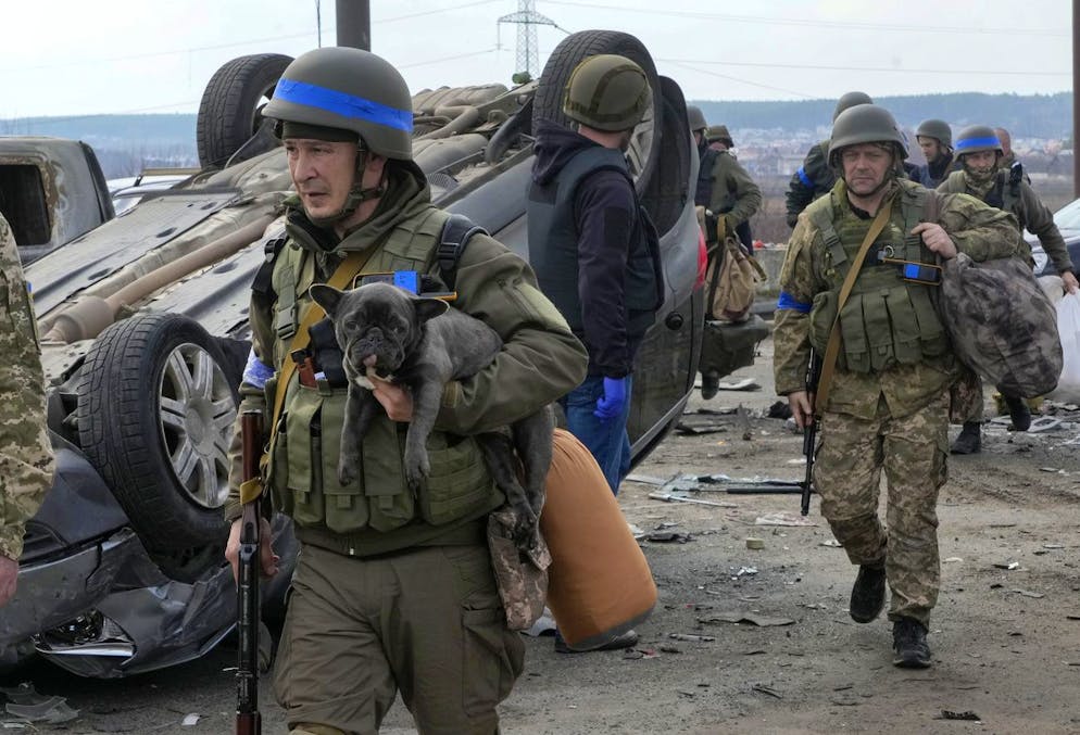 A Ukrainian soldier carries a dog saved from under the ruins of houses destroyed by the Russian forces in Irpin close to Kyiv, Ukraine, Thursday, March 31, 2022. The more than month-old war has killed thousands and driven more than 10 million Ukrainians from their homes including almost 4 million from their country. (AP Photo/Efrem Lukatsky)