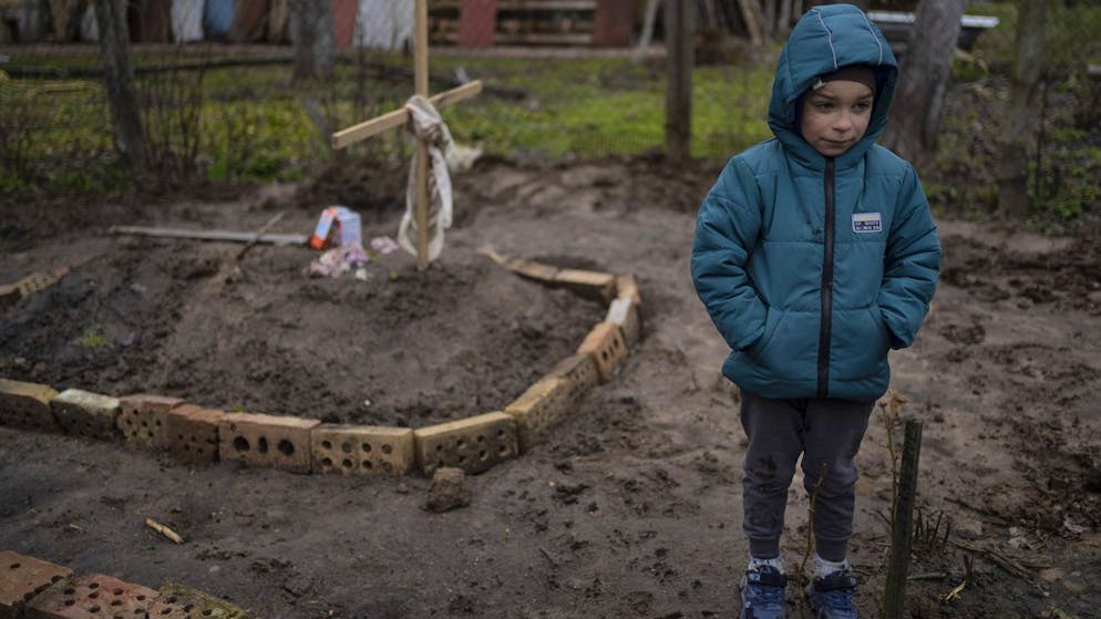 In the courtyard of their house, Vlad Tanyuk, 6, stands near the grave of his mother Ira Tanyuk, who died because of starvation and stress due to the war, on the outskirts of Kyiv, Ukraine, Monday, April 4, 2022. ( AP Photo / Rodrigo Abd)