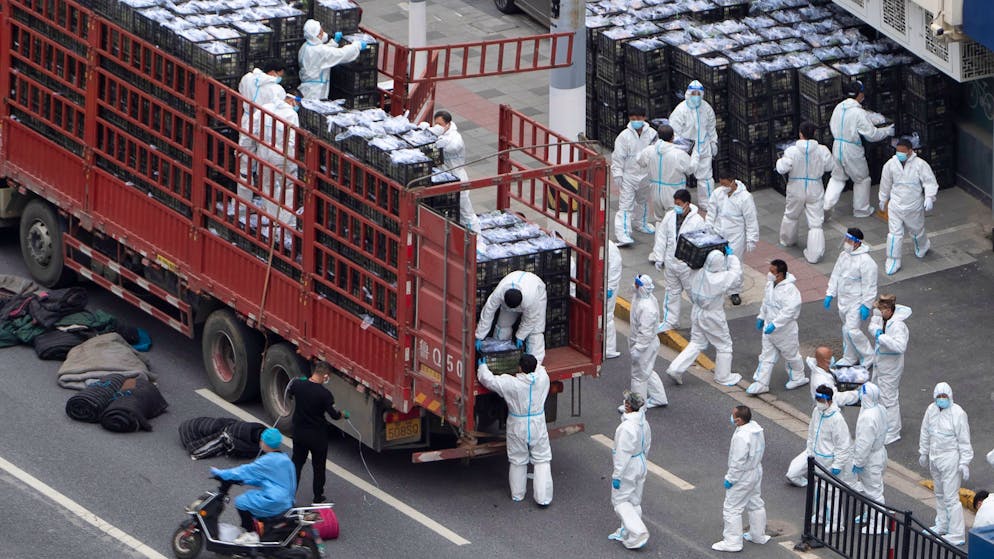 FILE - Workers in PPE unload groceries from a truck before distributing them to local residents under the COVID-19 lockdown in Shanghai, China, on April 5, 2022. Residents of Shanghai are struggling to get meat, rice and other food supplies under anti-coronavirus controls that confine most of its 25 million people in their homes, fueling frustration as the government tries to contain a spreading outbreak.(Chinatopix Via AP, File)