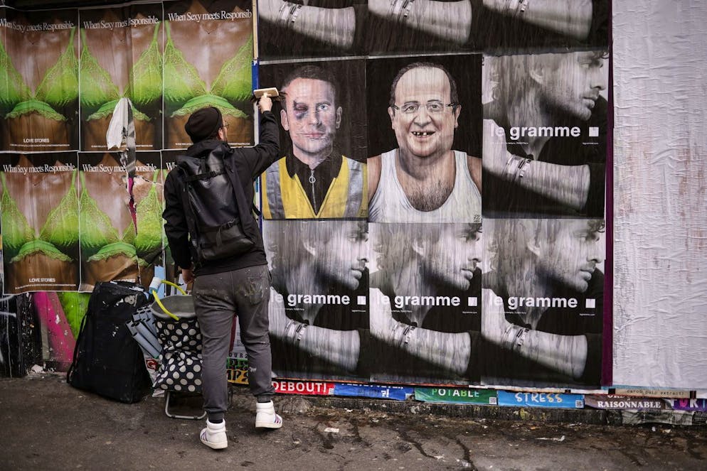 epa09874030 French street artist Jaeraymie pastes elections posters depicting caricatures of French President Emmanuel Macron (L) and French former President Francois Hollande (R) in the streets of Paris, France, 06 April 2022. Jaeraymie says he caricatures French Presidential candidates who stigmatized a social group of people with words or actions. The first round of the French presidential election will take place on 10 April and the second round on 24 April. EPA/YOAN VALAT