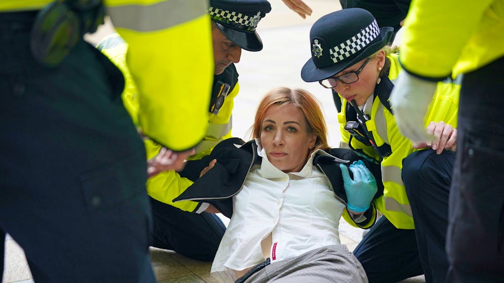 Police carry away an activist from Extinction Rebellion who glued herself to the reception of the Shell building on the Southbank in London. Wednesday April 13, 2022. (Yui Mok/PA via AP)