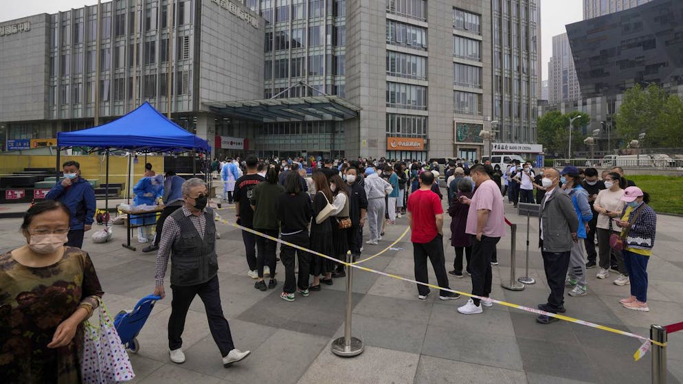 Residents and office workers wearing face masks line up for mass coronavirus testing outside a commercial office complex at the central business district, Monday, April 25, 2022, in Beijing. (AP Photo/Andy Wong)