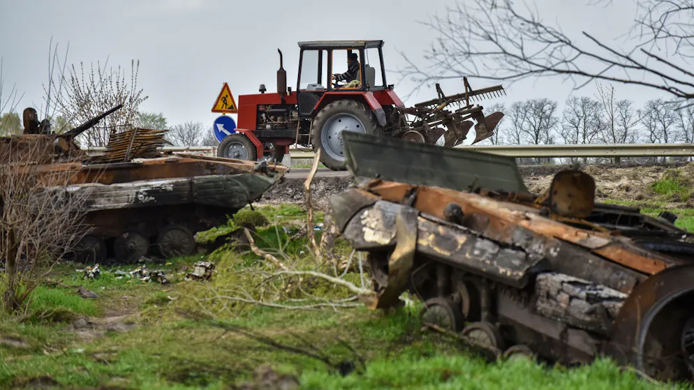 Ein Traktor passiert am 25. April im Dorf Rusaniw nahe Kiew ausgebrannte russische Schützenpanzer.