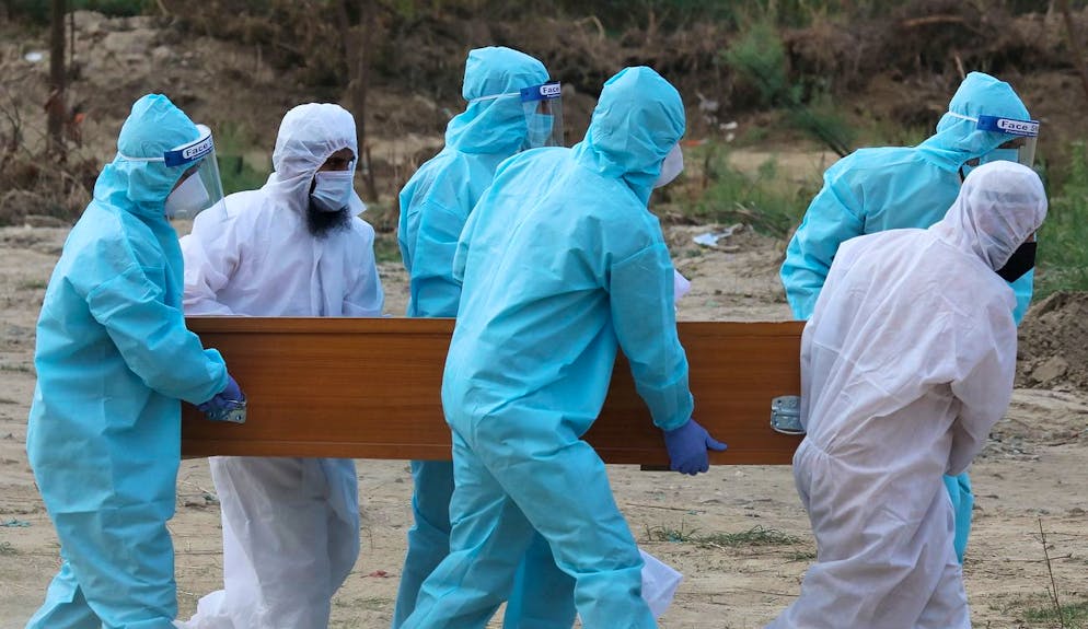 epa08488737 Relatives wearing personal protective equipment caarry coffin into a grave during funeral service of COVID-19 victim at designated area only for coronavirus funerals at the burial site in New Delhi, India, 16 June 2020. Indian government has decided to provide relaxation in the ongoing lockdown but it will continue until 30 June, in 'containment zones.' However Delhi reportedly witnessed an increase in deaths related to coronavirus and corona virus positive cases reported on a single day on 15 June. EPA/HARISH TYAGI